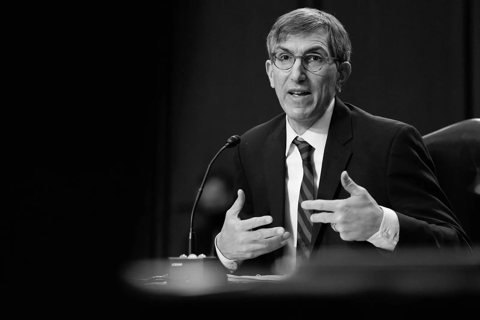 A man in a suit speaks at a hearing.
