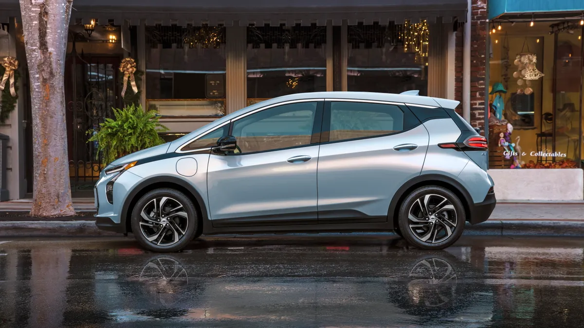 A 2022 Chevy Bolt EV parked in front of a bakery in an urban setting.