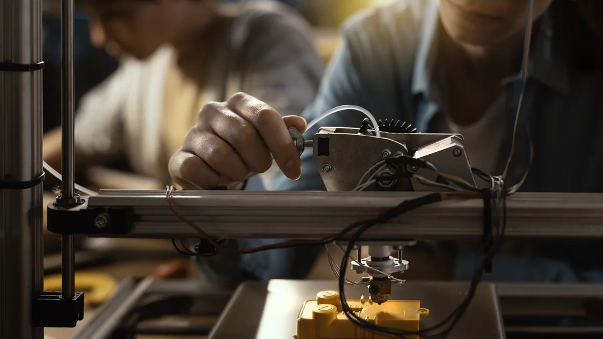 A student works with a 3D printing machine