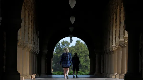 Two people walk on Stanford University's campus.