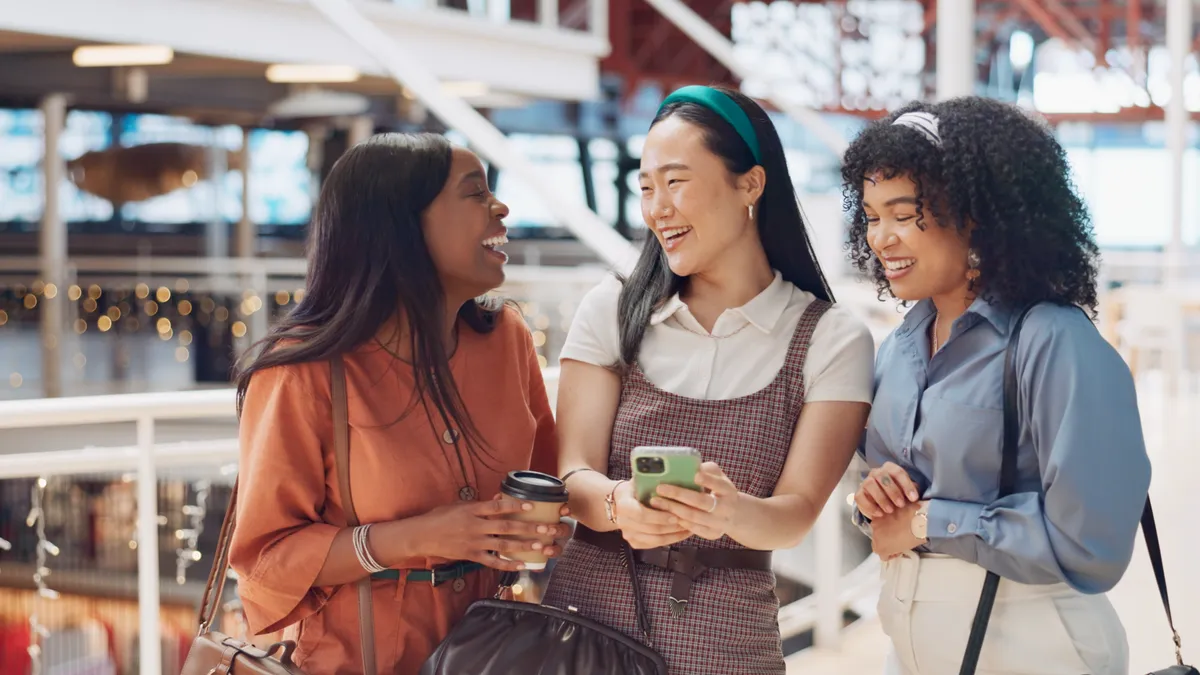 Young women looking at their phone and laughing with each other.