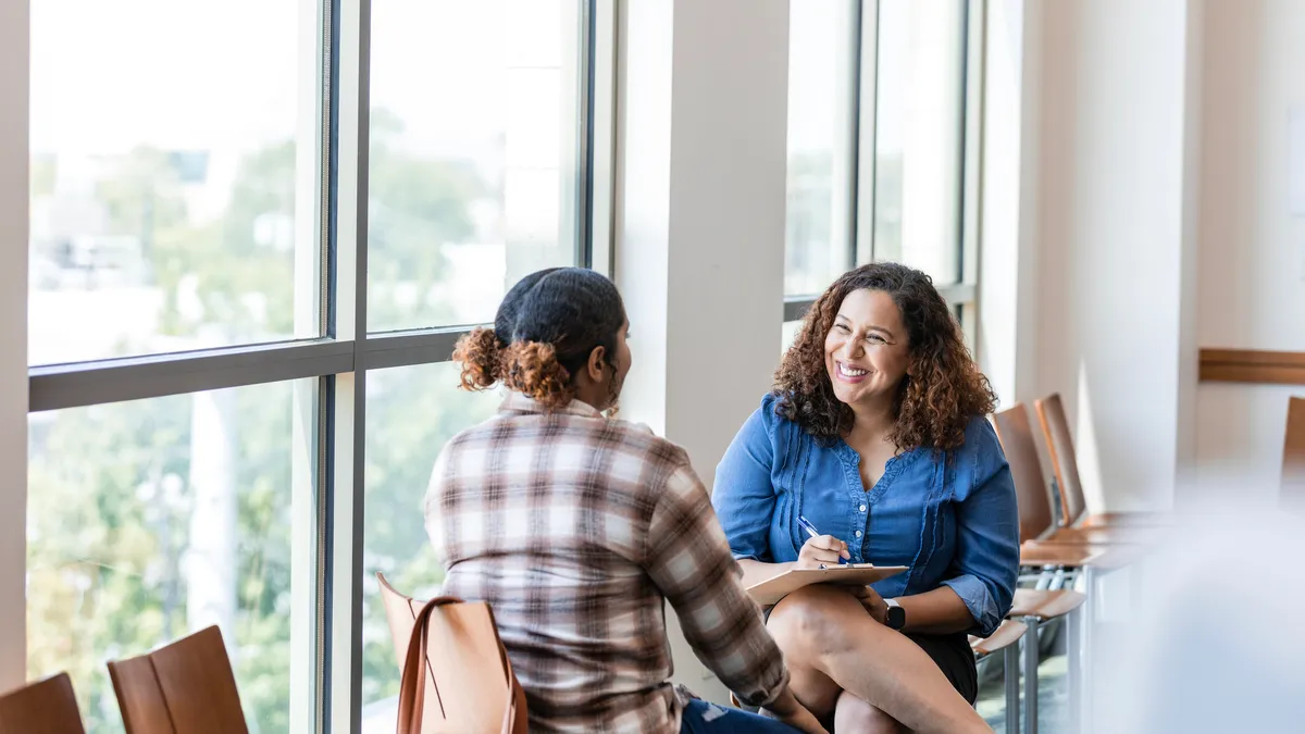 Two people chat on a college campus.