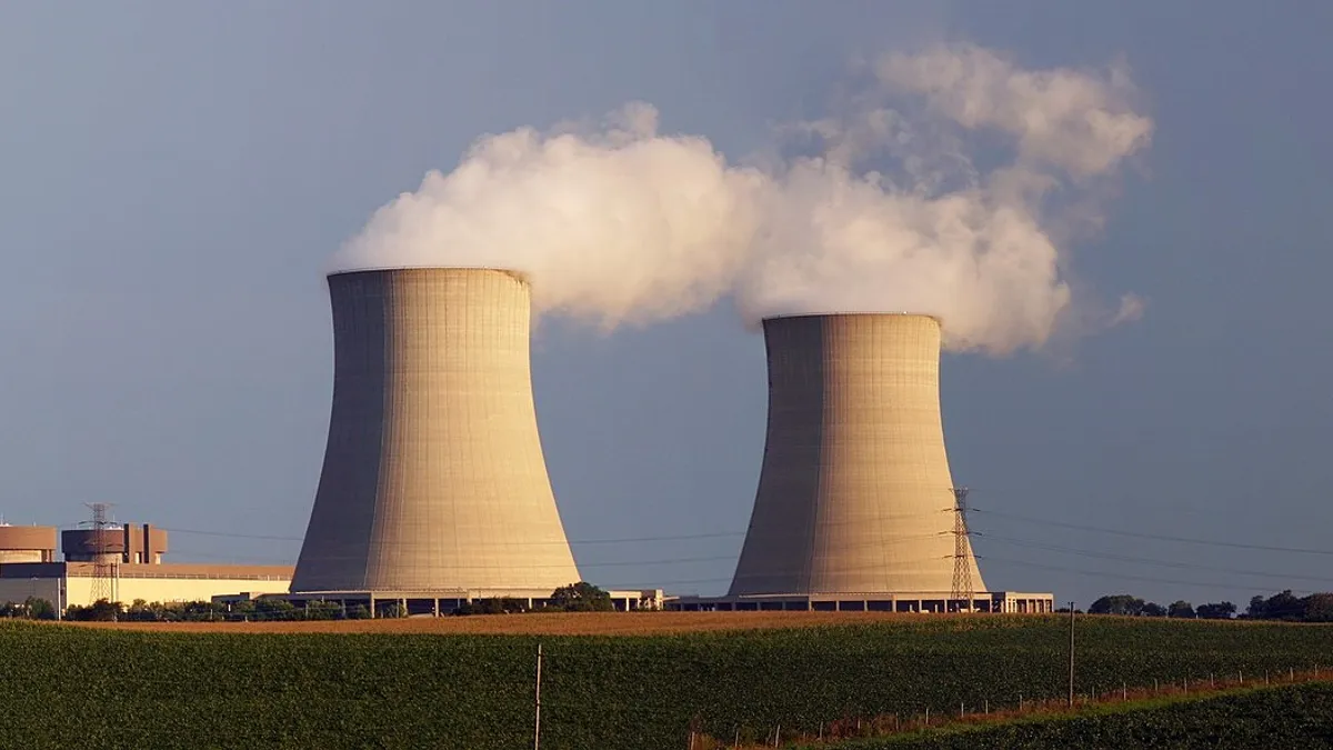 A nuclear power plant with steam billowing from two cooling towers.