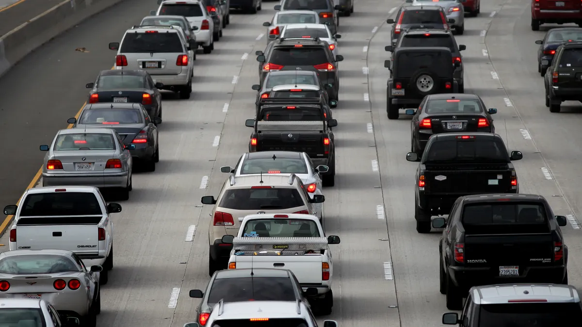 Cars are backed up bumper-to-bumper on a multilane highway, seen from behind.