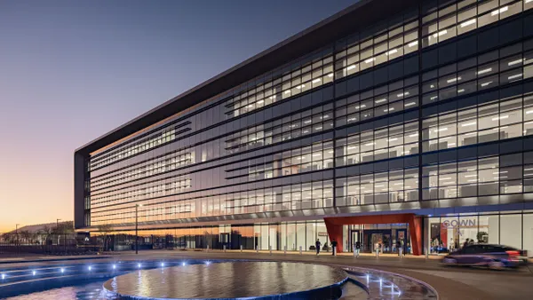 A horizontally long building with glass windows on the front during dusk.