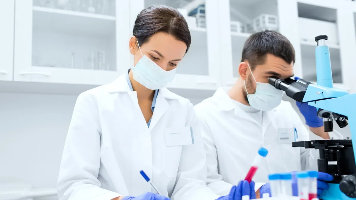 scientists with clipboard and microscope in lab