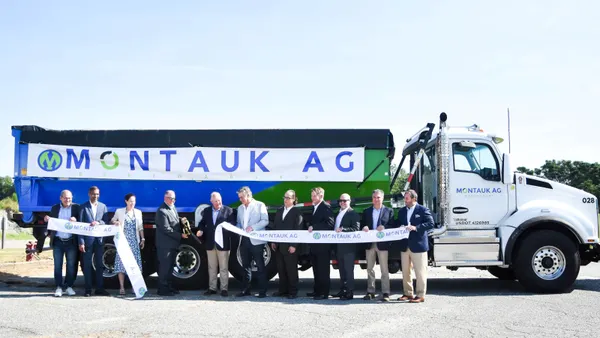 Several people gather to cut a ribbon in front of a truck with the Montauk Renewables logo.