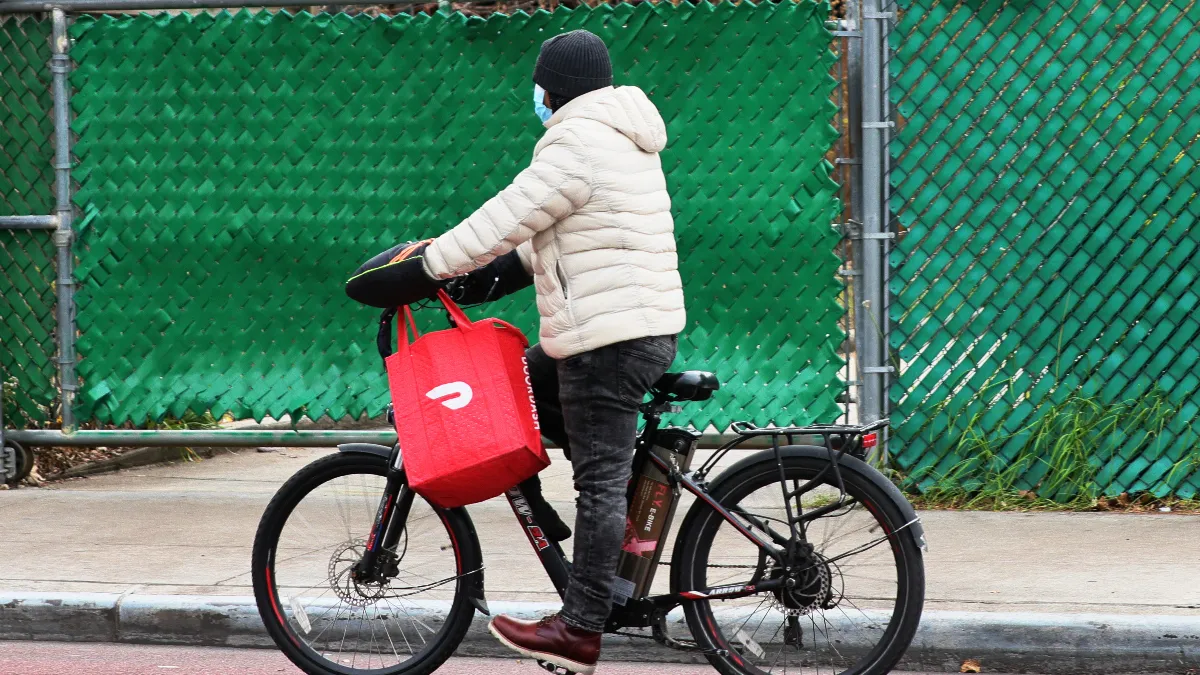 A bike courier with a red delivery bag.