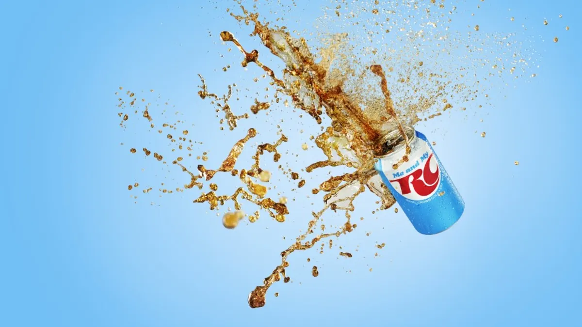 A RC Cola is pictured in the air, spilling soda.