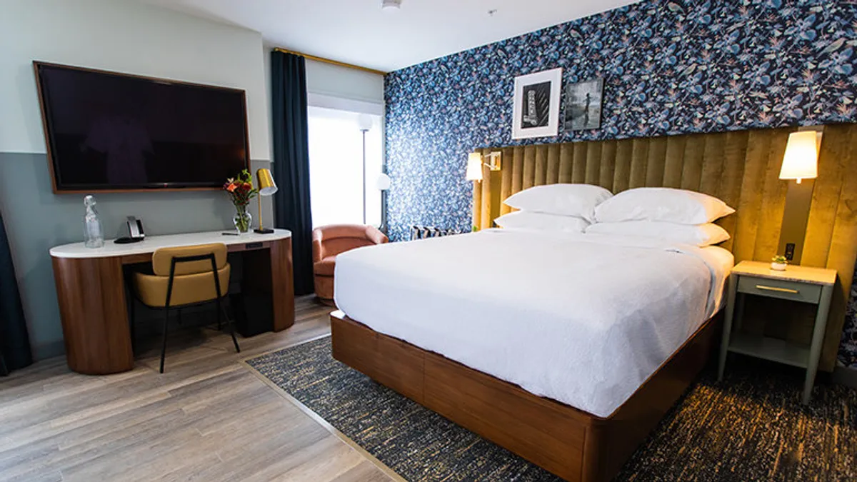 A bed in a room with blue patterned wallpaper.