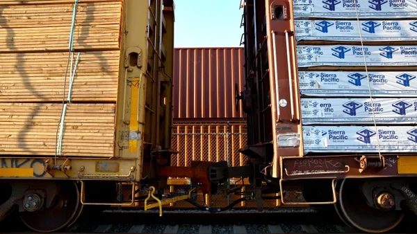 Freight rail cars carrying lumber sit on rail tracks