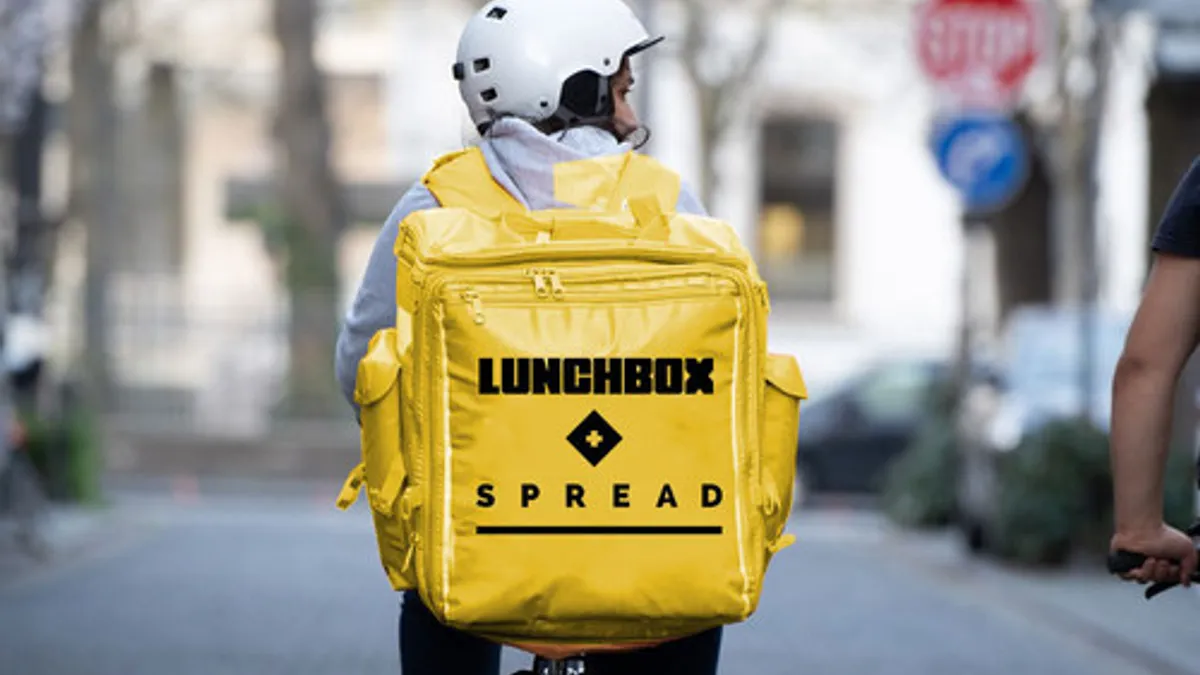 An image of a bike rider with a yellow backpack that says "Lunchbox" on it