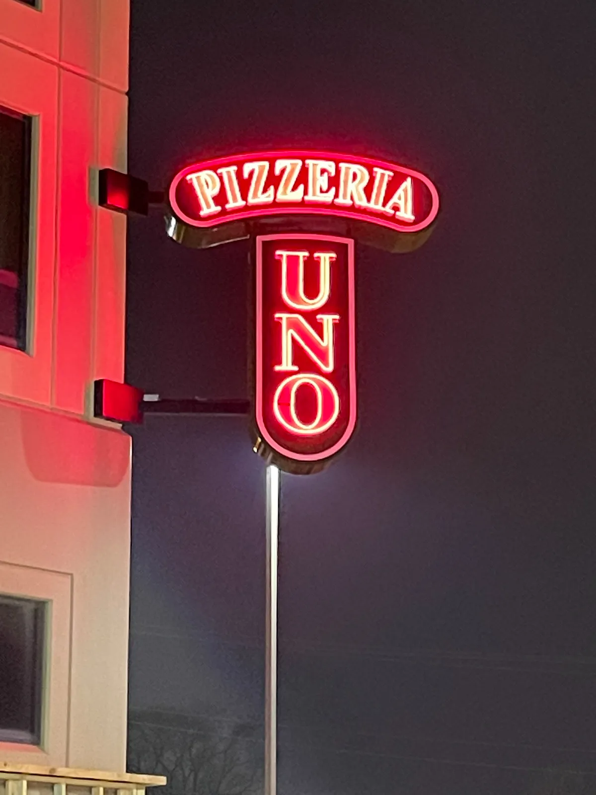 An image of a red neon sign that says Pizzeria Uno on the side of a building