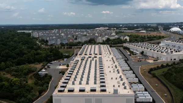 A large warehouse-like building with homes in the background.