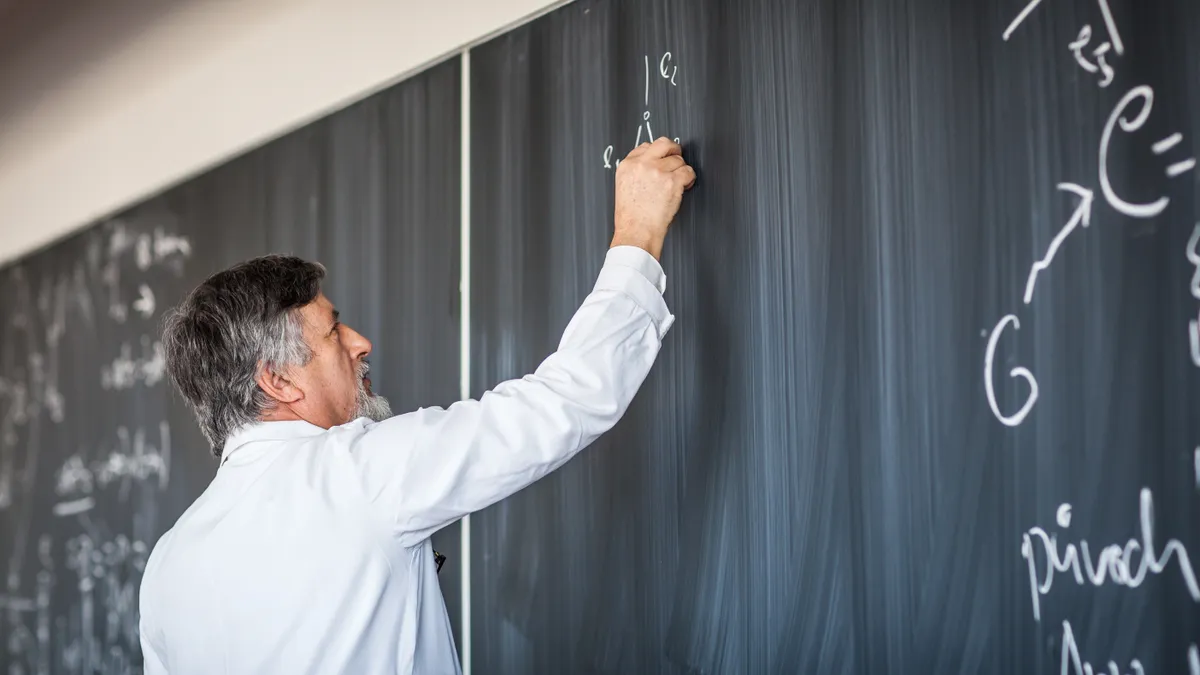 A person writes on a chalkboard.