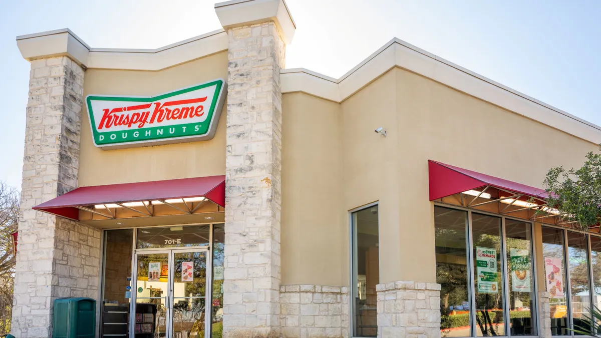 A biege building with signage in red and green that says Krispy Kreme Doughnuts