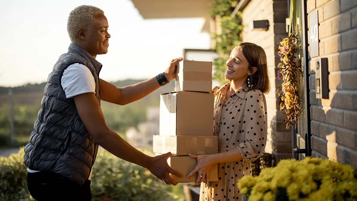 Person handing packages to another person at door