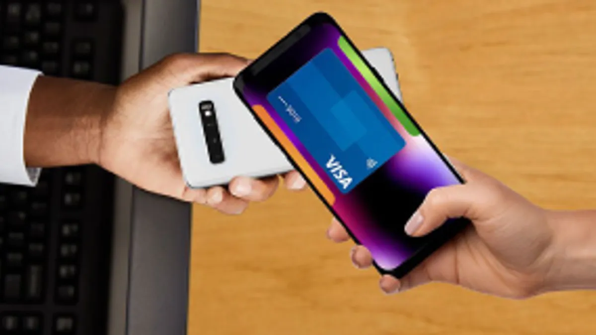 Hand with phone showing Visa card image passes a hand holding another phone