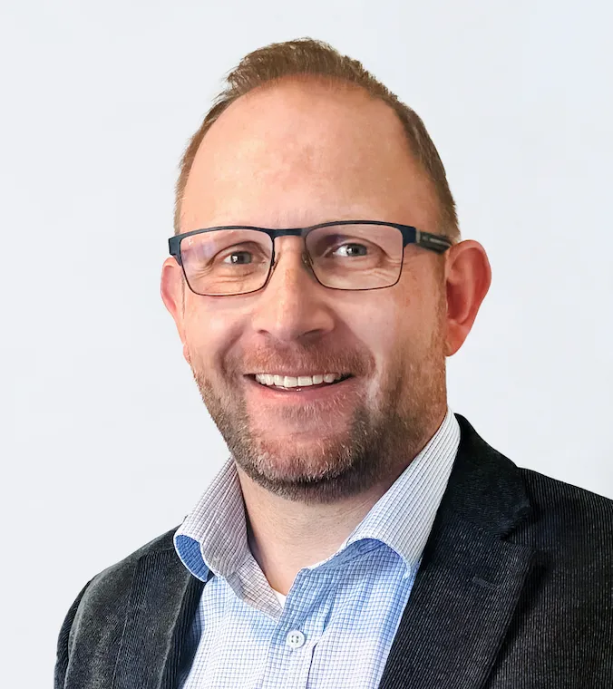 A headshot of Haselden Construction executive Daniel Bates shows a man in sports coat and collared shirt.