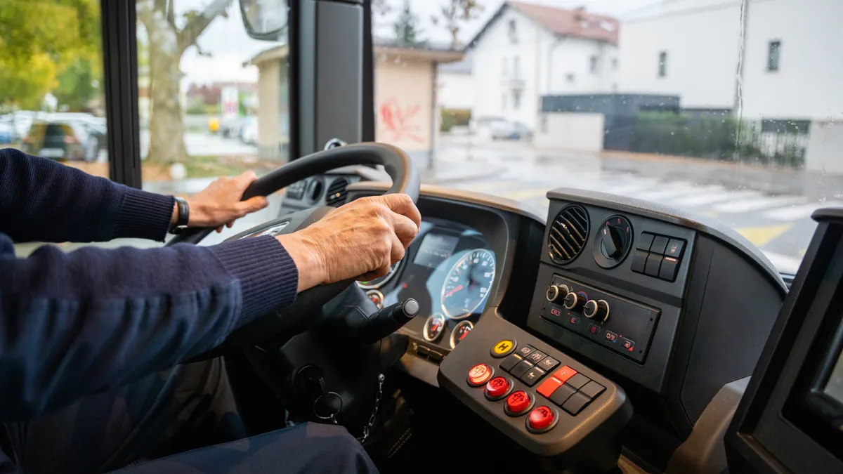 Close up of a person's hands on a bus steering wheel