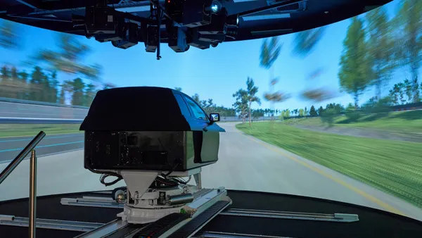 Hyundai's Driving Simulator in front of a large a 270-degree curved-display showing a test track that mimics real-world driving.