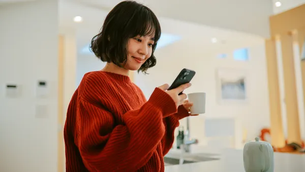 A woman checks her phone inside her home.
