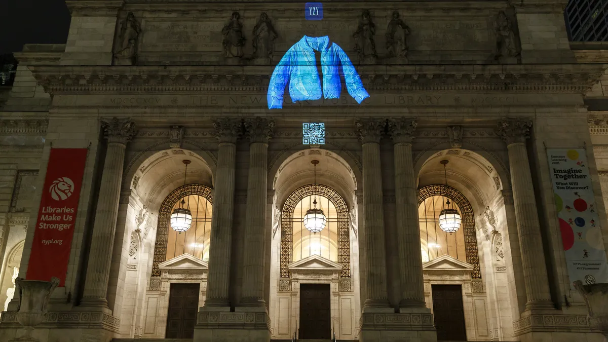 Images of the "Yeezy Gap" logo, a sky-blue puffer jacket and a QR code are projected onto the New York Public Library building.