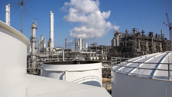 An outdoor chemical facility with a white smoke emitting from one of the units.