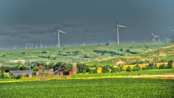 A farm with wind turbines in the background.