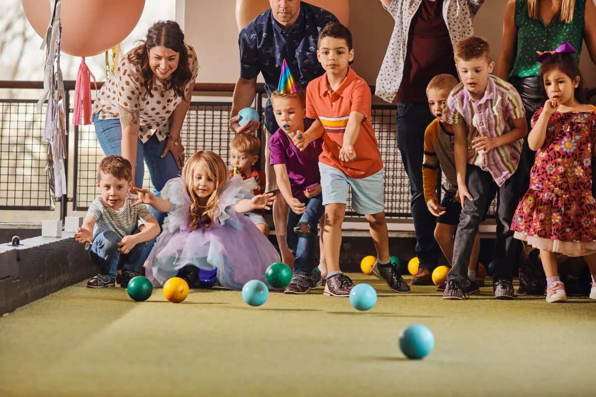 Kids in party hats playing bocce ball at Pinstripes