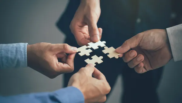 Hands joining puzzle pieces