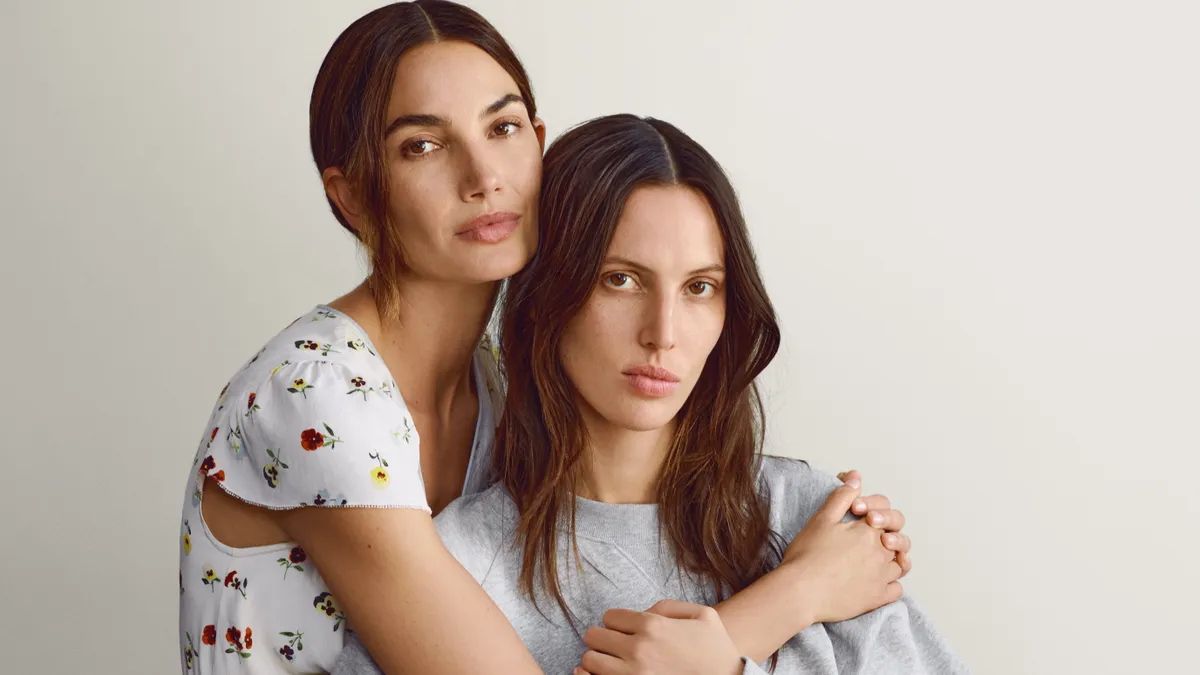 Two models sit together, hugging, wearing pieces from the Gap and Dôen collection.