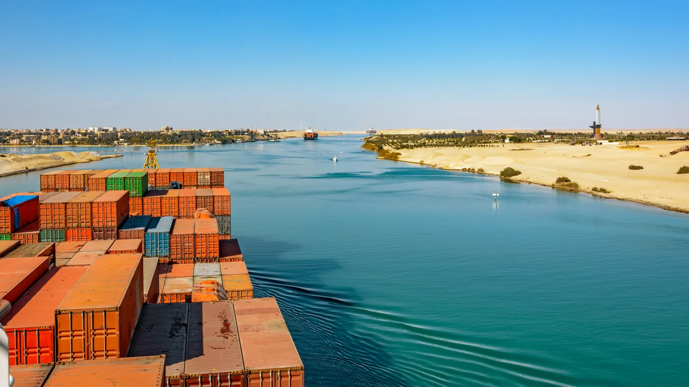 Industrial container ship passing through Suez Canal with ship's convoy, view on the bow from the captain bridge.
