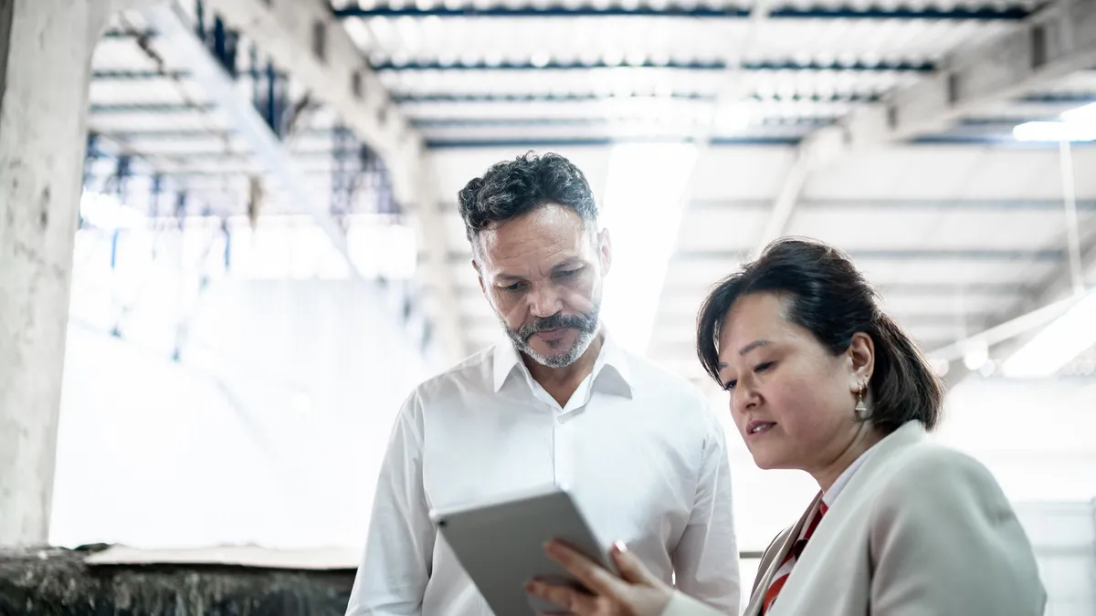 Coworkers talking and using digital tablet in a meeting at a factory