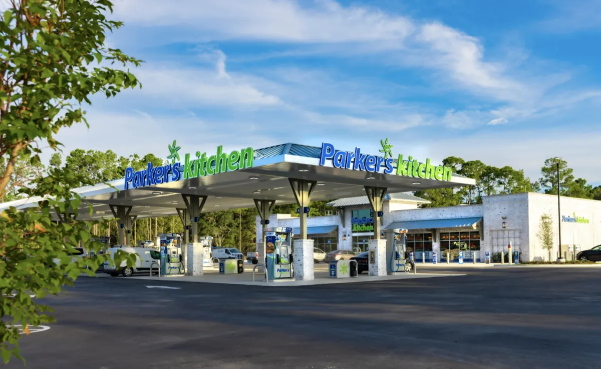 A photo of the exterior of a gas station and convenience store. Signs on the fuel canopy and store say Parker's Kitchen.