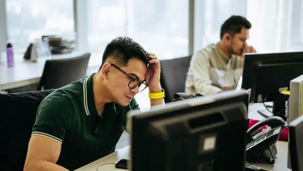 Two men looking stressed working in an office.