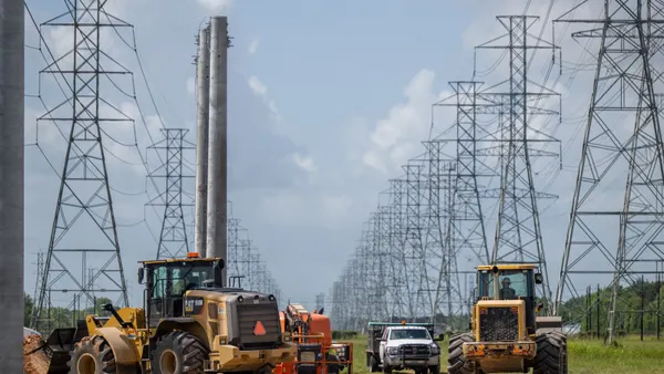 Heavy equipment sits near high-voltage electric power lines.