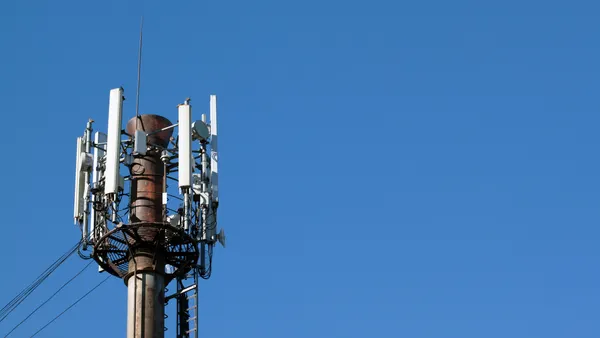 An electronic tower stands against a blue sky.