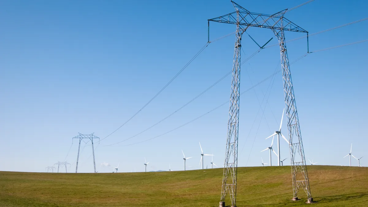 Large electric power transmission lines and modern wind turbines generating electricity in central California.