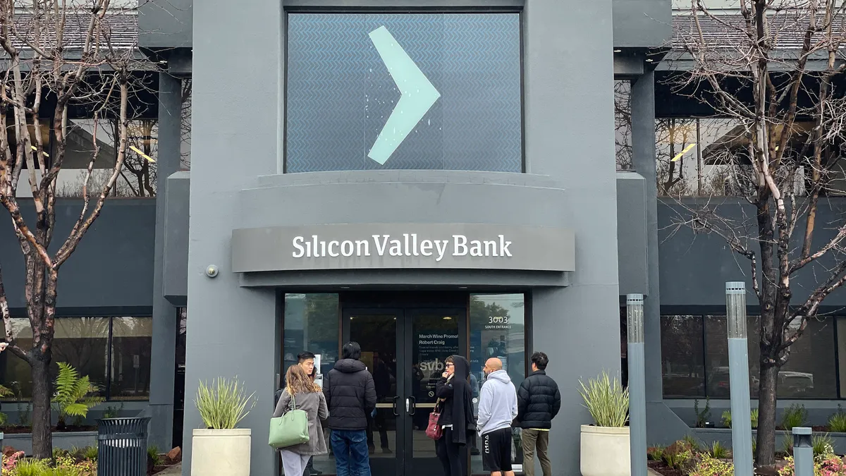 People stand outside a closed bank branch.