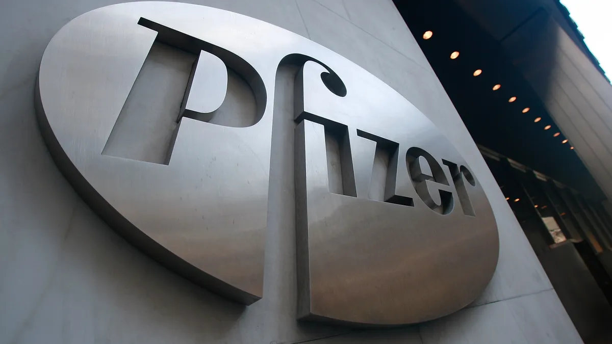 A chromatic Pfizer sign hangs on a building façade