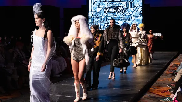 Models walk down a runway with the word "Snowfly" written on the back wall.