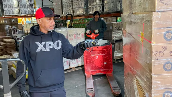 XPO driver Steadman "Steve" Mitchell scans a pallet of cup lids as it comes off his truck at M&K Food.