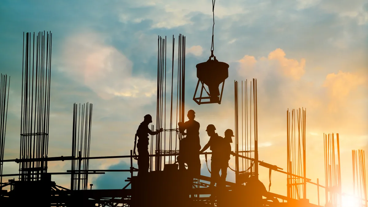 Construction workers perform tasks at height while wearing fall protection.