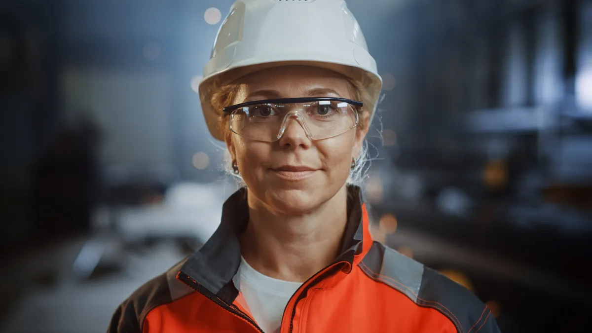 A construction worker in a white safety hat and orange work jacket.