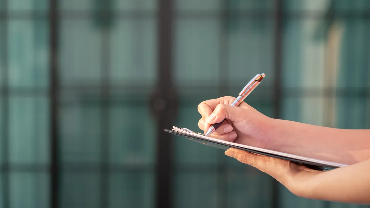 A closeup shot of a hand holding a clipboard.