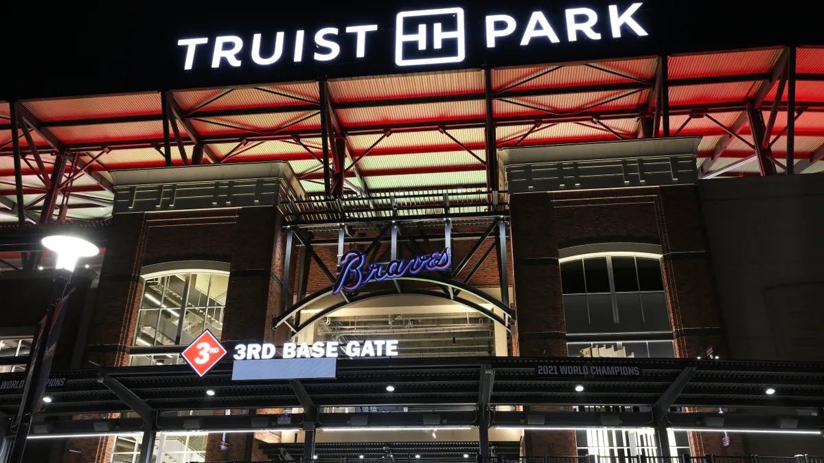 Nightime view of entrance to baseball stadium. Bright signs read "Truist Park," "Braves" and "3rd base gate."