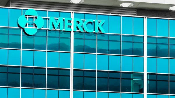 A sign spelling Merck hangs on the side of an office building