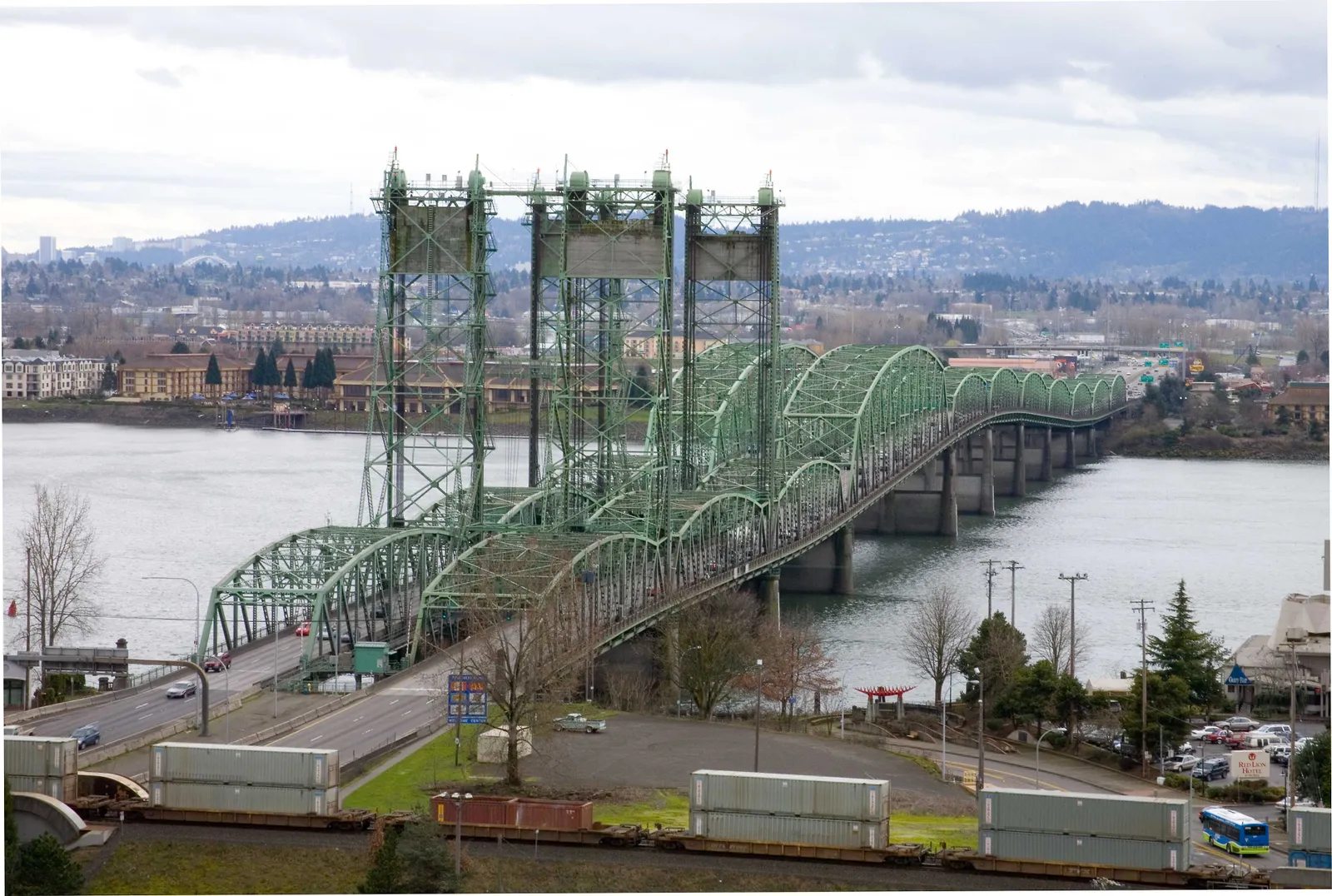 Twin green bridges cross a body of water.