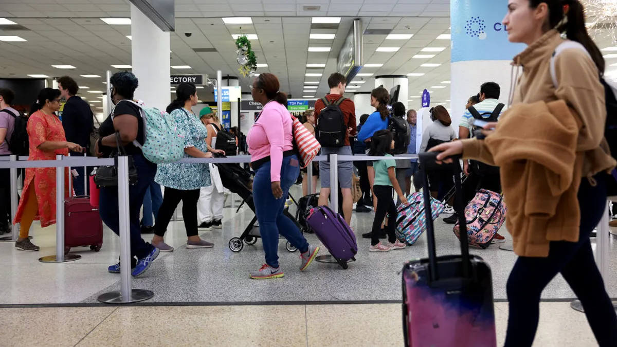 Travelers stand in line for a TSA checkpoint at the Miami International Airport on December 19, 2022 in Miami, Florida.